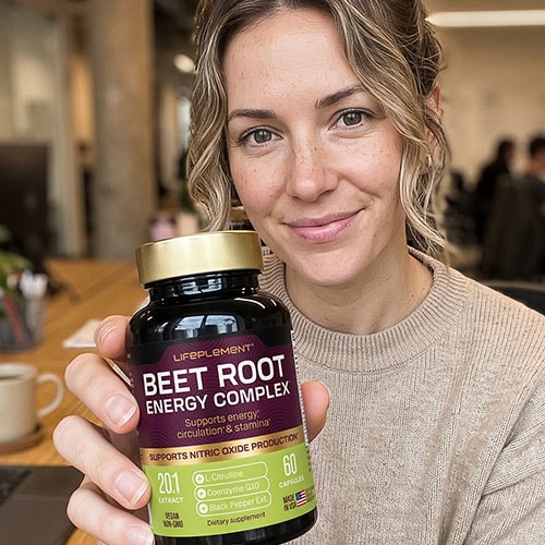 Woman holding LIFEPLEMENT Beetroot Supplements bottle in a cafe setting.